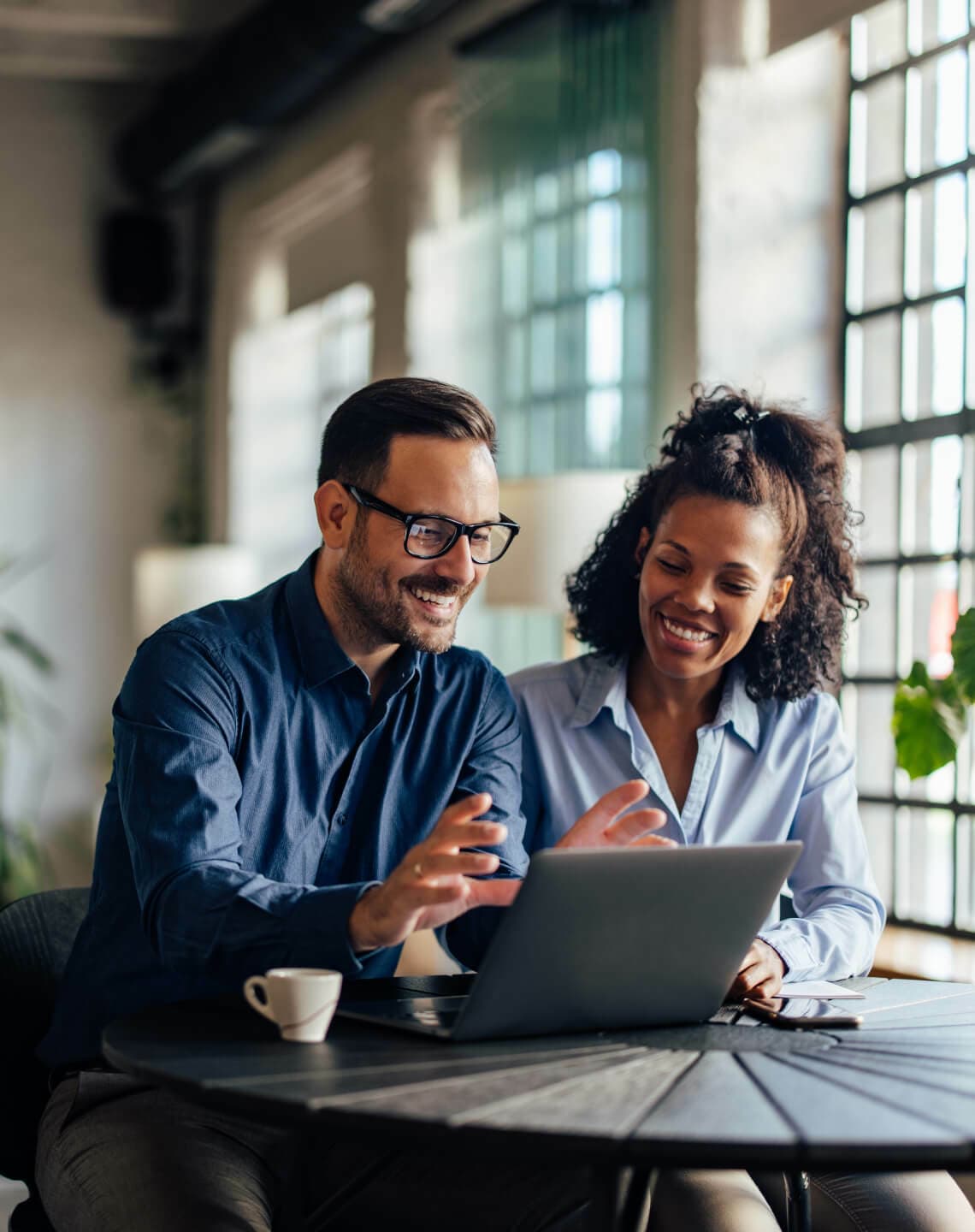 two coworkers looking at a laptop screen and working in an office